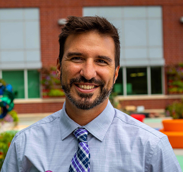 man in professional attire standing outside of hospital