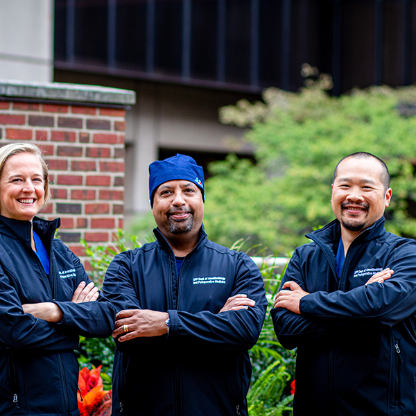 Team of three providers stands outside a hospital.