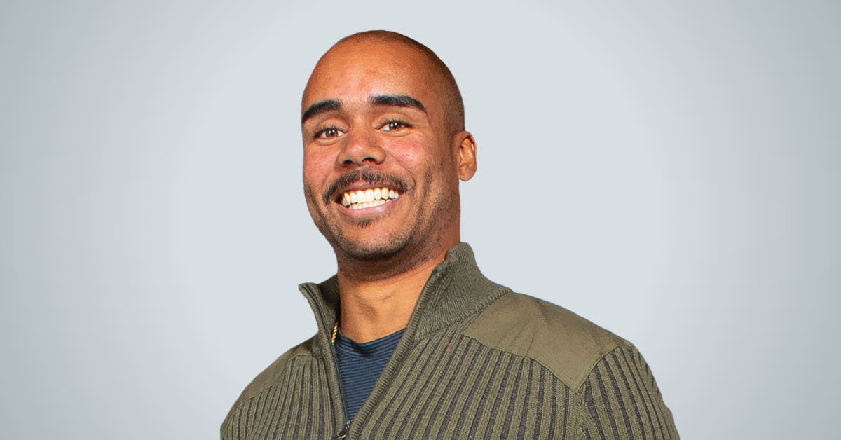 Young man smiles at camera in a studio setting.
