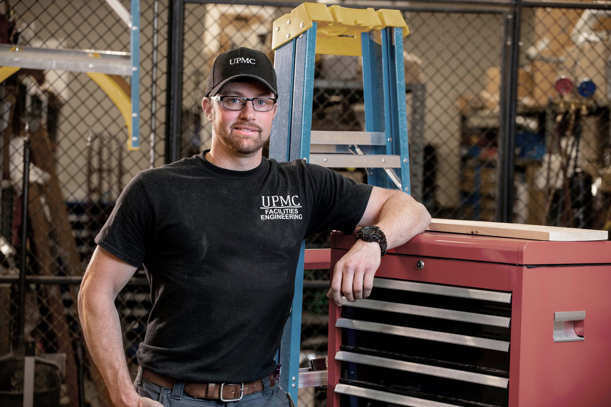 Man in classes and t-shirt leans on a tool chest.