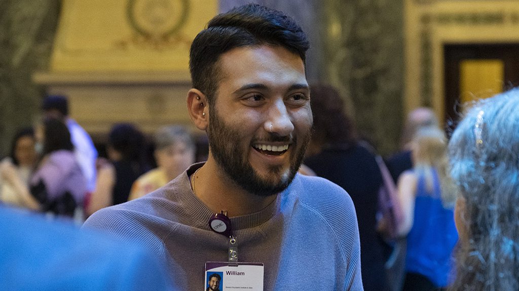 Young man at event talking to others.