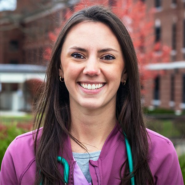 Young woman with brown hair smiling outside of hospital.