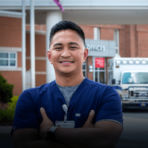 Middle aged nurse stands in front of emergency room.